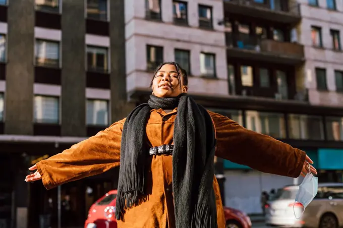 Young woman with arms outstretched in city