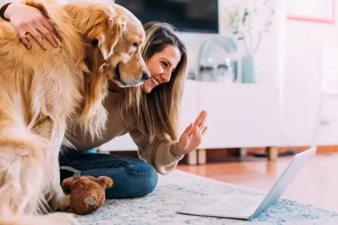 Italy, Young woman with dog looking at laptop