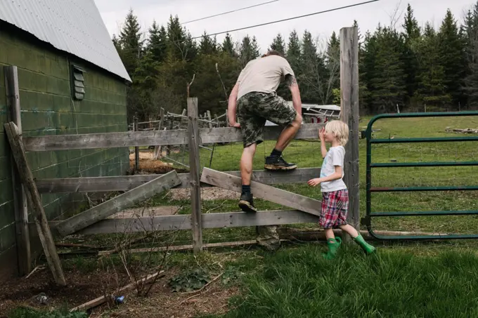 Canada, Kingston, Boy (8-9) assisting father climbing over fence in field