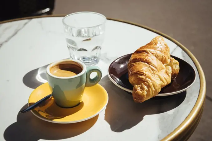 France, Paris, Croissant, coffee and glass of water on sidewalk cafe table