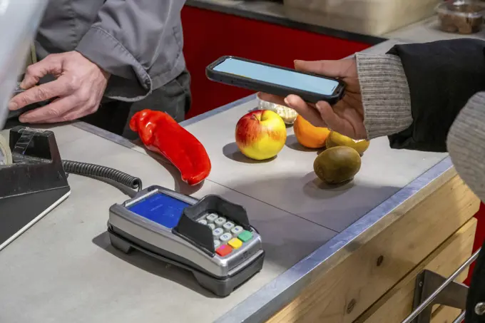 Adult female paying for fruit and vegetables.