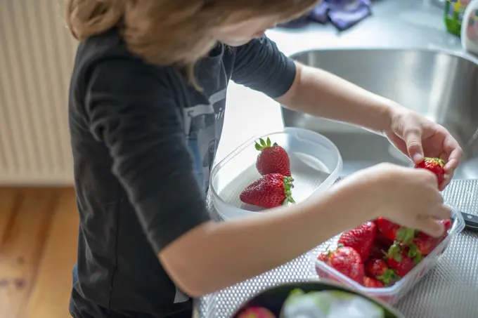 Young boy cutting healthy strawberries with help from his mum