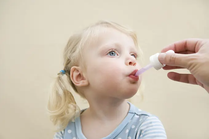 Young child receiving medicine from a dropper