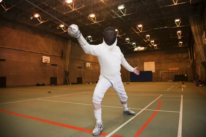 Fencer in midlunge at the gymnasium ready for competition