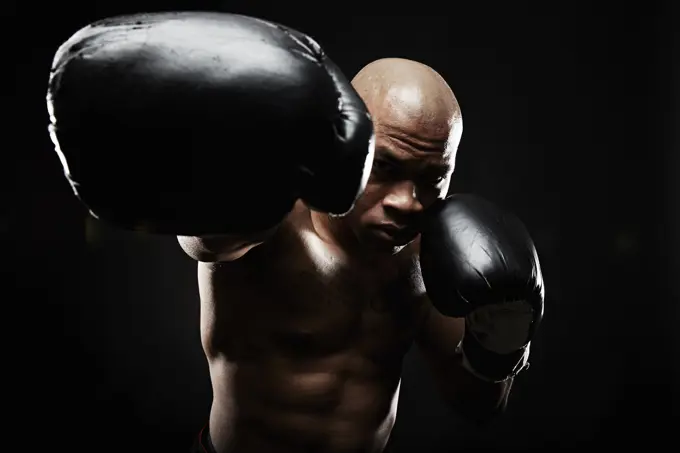 Boxer with black boxing gloves punching towards camera