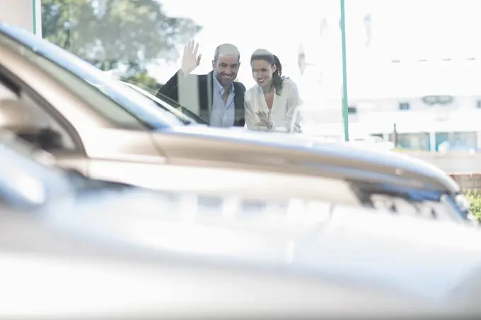 Mid adult couple looking through car dealership window