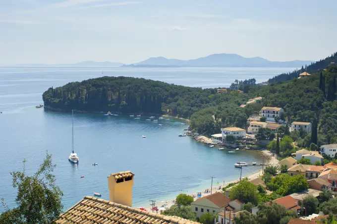 View of coastal village rooftops and bay, Corfu, Greece