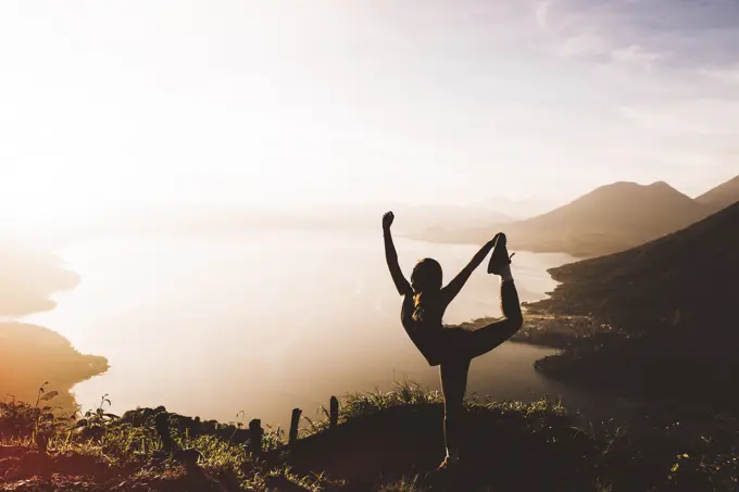 Silhouetted view of young woman posing at sunset above Lake Atitlan, Guatemala