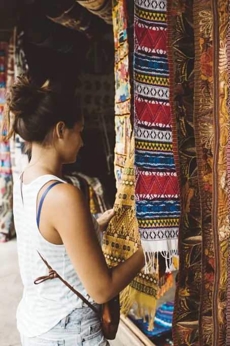 Young woman shopping for textiles at market stall,  Lake Atitlan, Guatemala