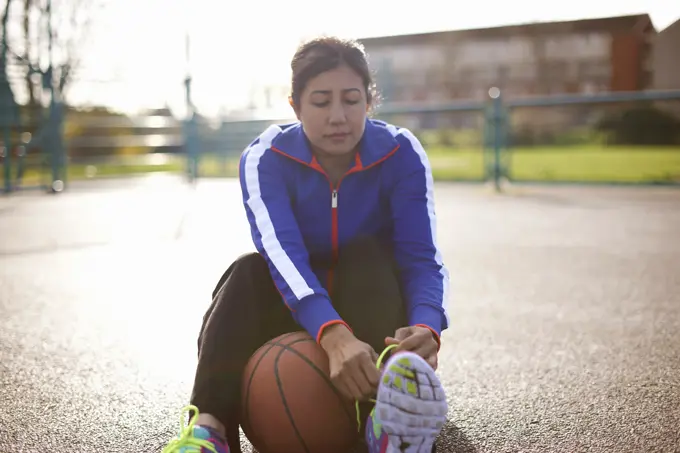 Mature female basketball player tying trainer laces