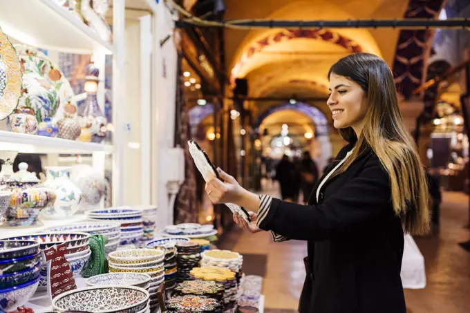 Young woman looking at crockery on market stall, Istanbul, Turkey