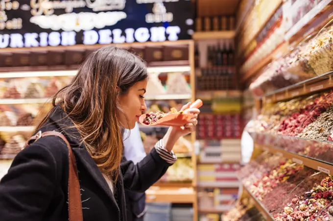 Young woman smelling food in market, Istanbul, Turkey