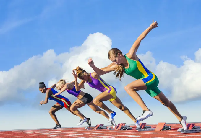 Four female athletes on athletics track, starting race