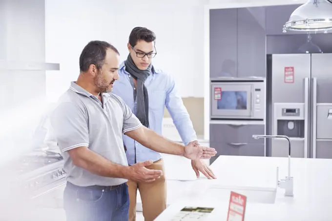 Salesman and young man in kitchen showroom