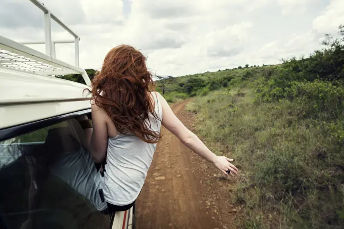 Woman sitting on door of vehicle in wildlife park, Nairobi, Kenya