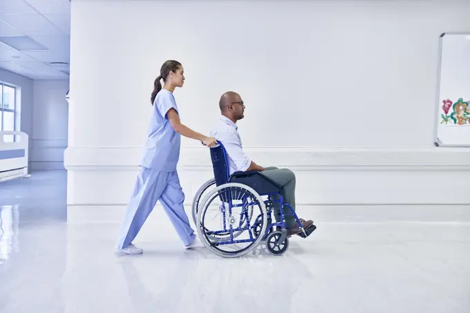 Doctor in hospital pushing patient in wheelchair