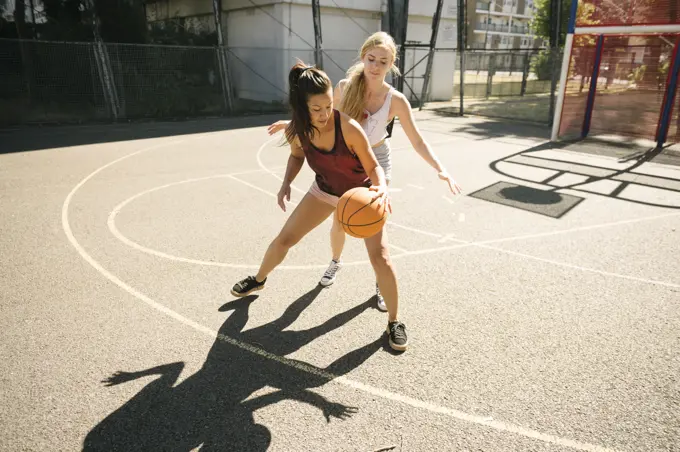 Two female basketball players practising on basketball court