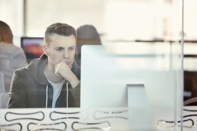 University student working at computer behind glass partition