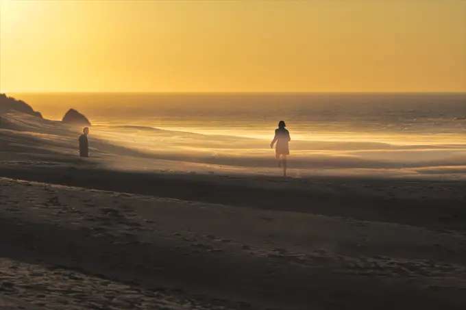 Couple on beach at Golden Bay at sunset, South Island, New Zealand