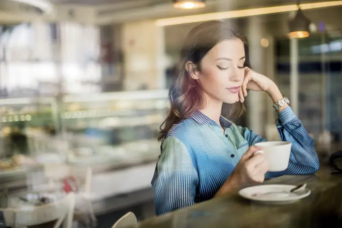 Beautiful woman at cafe window seat, Dubai, United Arab Emirates