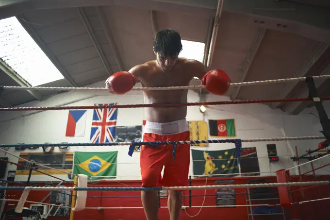 Boxer leaning on ropes of boxing ring