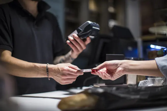 Close up of barista handing credit card to female customer