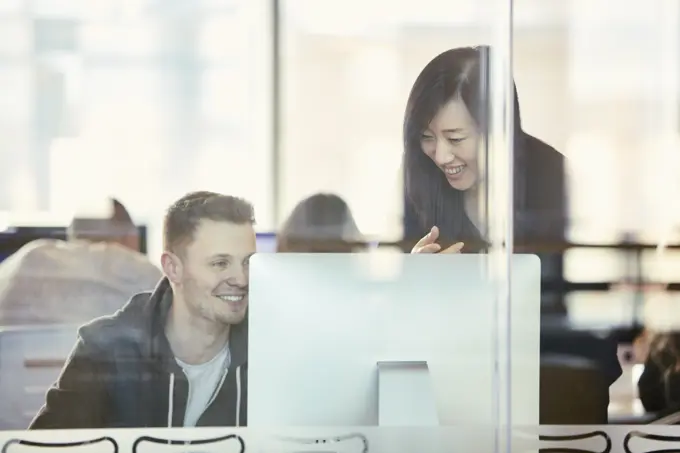 University students working at computer behind glass partition