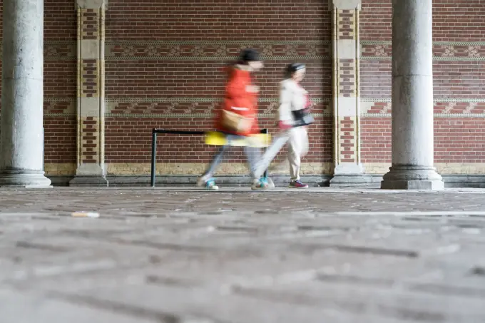 Blurred motion of people walking by brick wall, Amsterdam, Netherlands