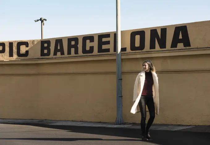 Female tourist strolling by wall with Barcelona in capital letters, Barcelona, Spain