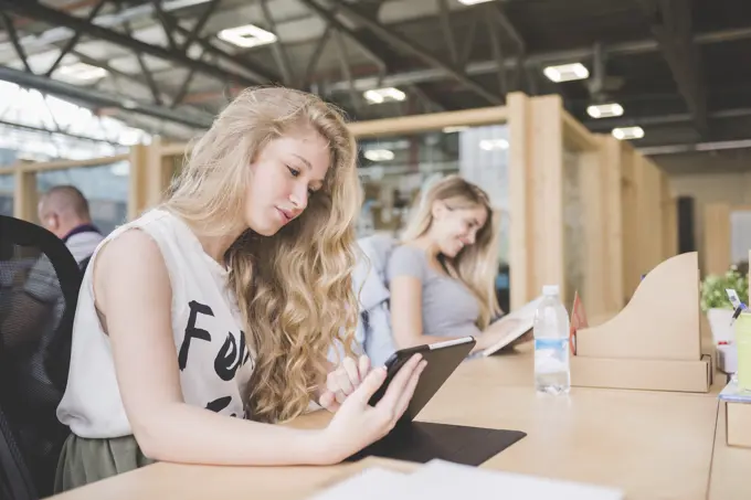 Co-workers working on digital tablet in open plan office