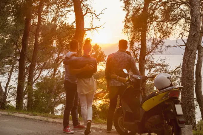 Two moped couples looking out at sunset from coastal road, Split, Dalmatia, Croatia