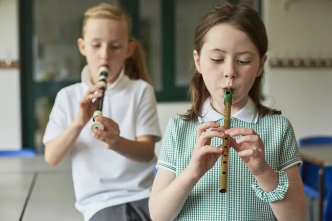 Two children practice playing the recorder during music class.