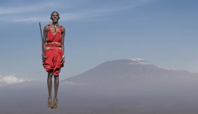 Masai man with traditional dress jumping in front of Mount Kilimanjaro, Amboseli, Rift Valley, Kenya