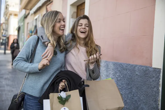 Friends out shopping and laughing in street