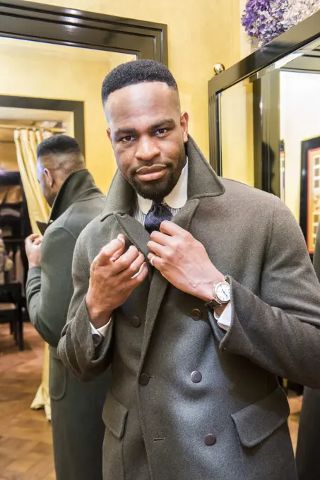 Male customer trying on coat in tailors shop, portrait