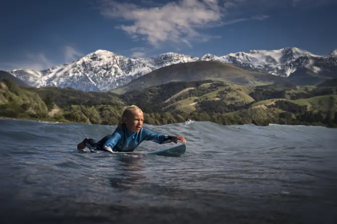 Young boy paddling on surfboard in sea, Kaikoura, Gisborne, New Zealand