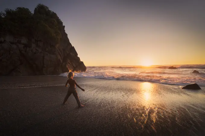 Boy standing on beach, looking at sunset, Kaikoura, Gisborne, New Zealand