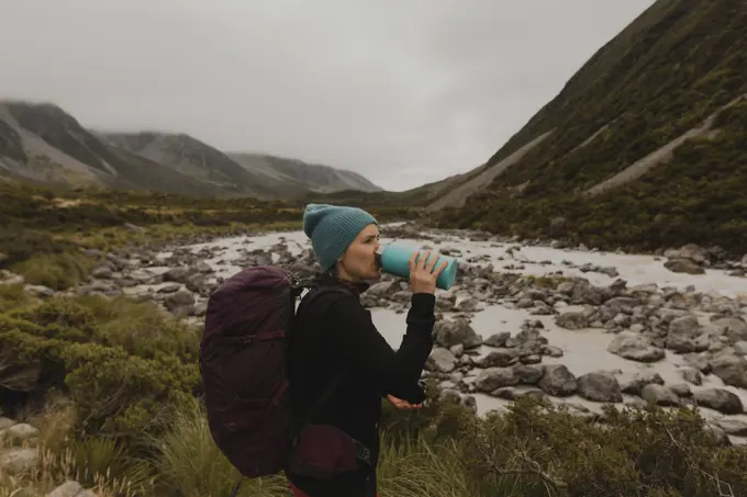 Hiker drinking, enjoying view of wilderness, Wanaka, Taranaki, New Zealand