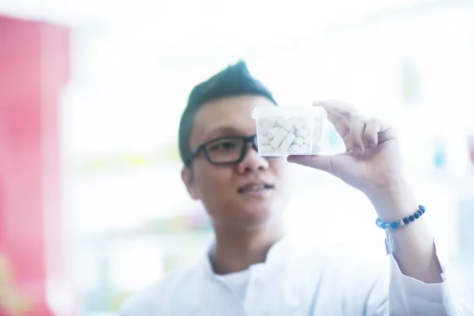 Young pharmacist showcasing a medicine package