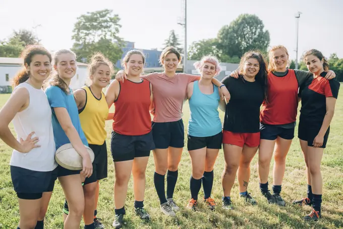 A diverse team of female athletes posing together with confidence on the field.