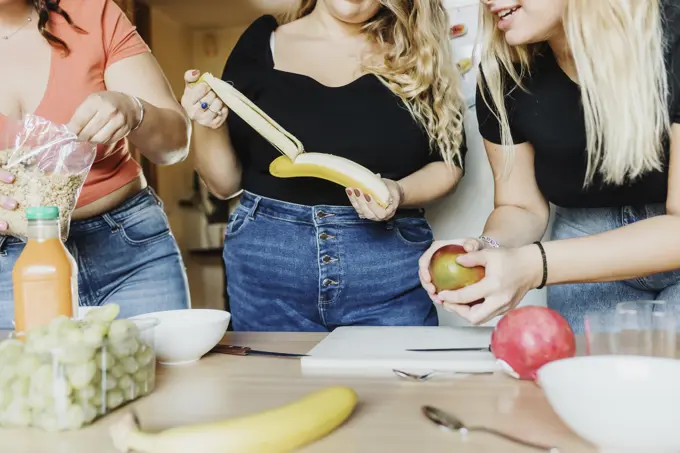 Friends sharing a fun moment while preparing a healthy meal together.