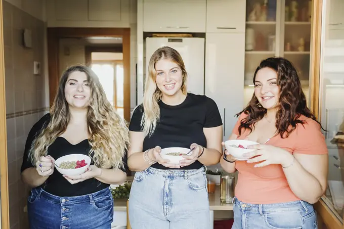 Three friends enjoying a healthy snack in the kitchen.