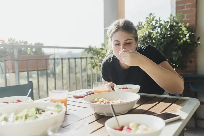 Woman enjoying a healthy breakfast on a sunny terrace