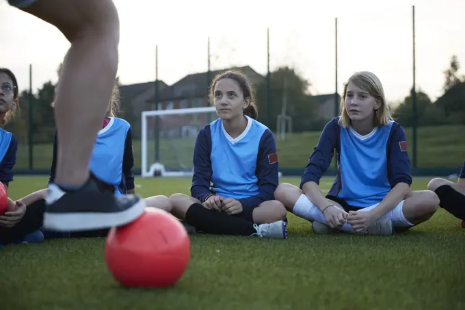 Young soccer players attentively listening to their coach at dusk