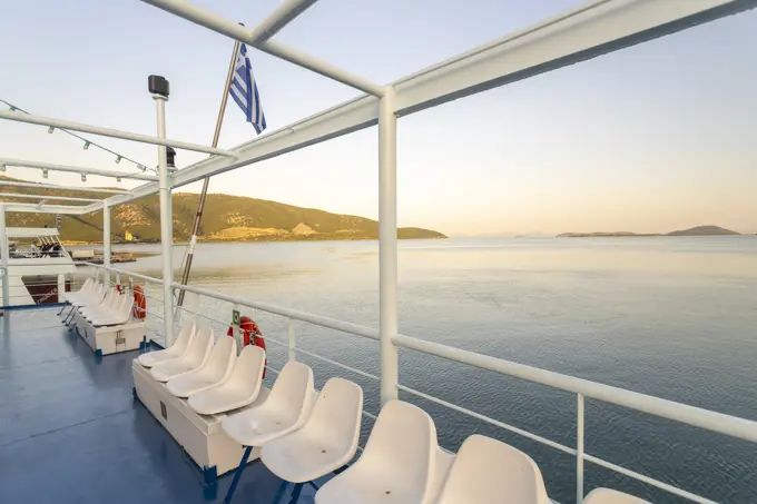 Greece, Igoumenitsa, Row of seats on ferry deck in sea at sunrise