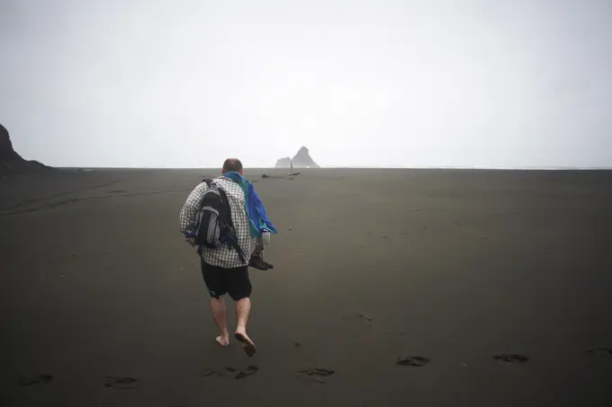 Man walking on Karekare beach, Karekare, New Zealand