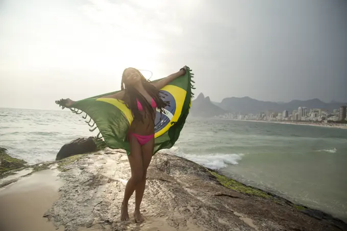 Young woman holding up Brazilian flag,  Ipanema beach, Rio De Janeiro, Brazil