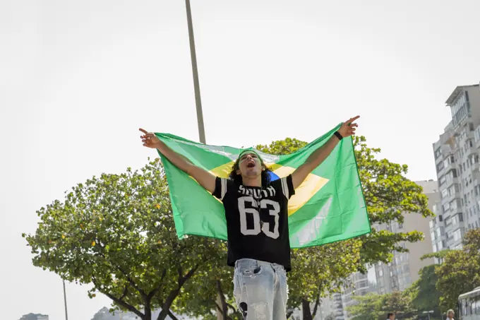 Young man holding up Brazilian flag, Copacabana, Rio De Janeiro, Brazil