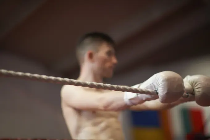 Boxer leaning on ropes of boxing ring