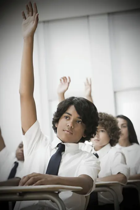 Eager student raising hand in a classroom setting.